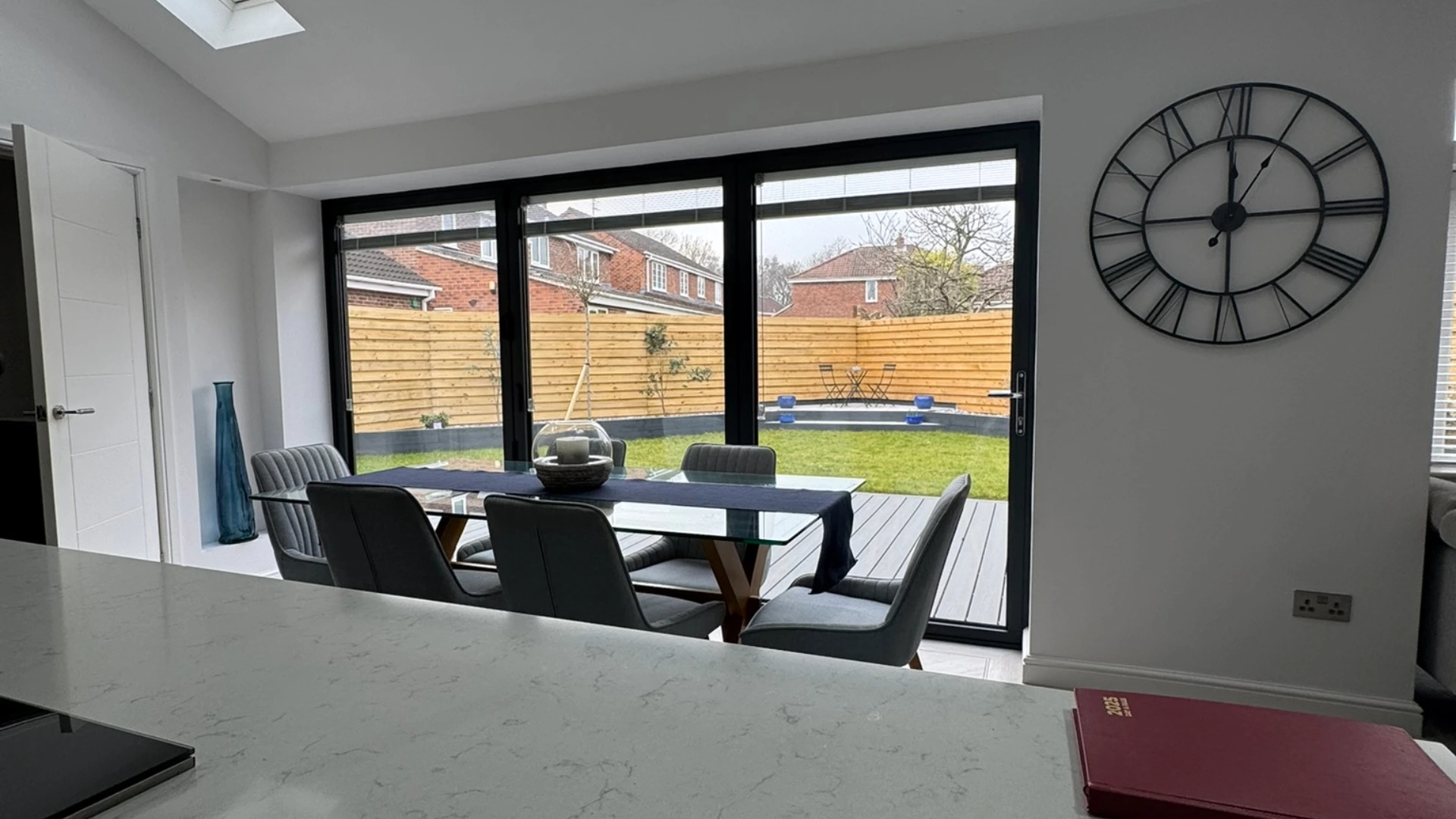 A kitchen with a large glass front, showing the back garden.