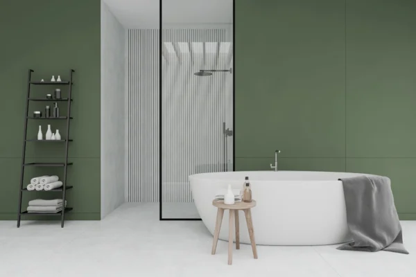A modern bathroom with a white oval tub, a black ladder shelf, and green walls.