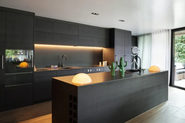An eye-level shot captures a spacious, modern kitchen with dark, textured wood cabinets and a matching island.