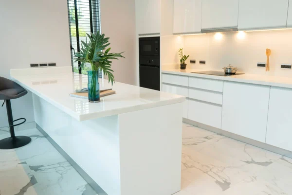 A sleek, modern kitchen with white high-gloss handleless cabinets and countertops.