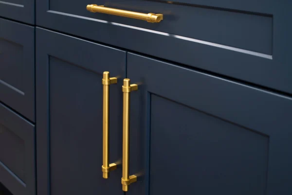 A set of deep navy-blue shaker kitchen cabinets with brass pull handles.