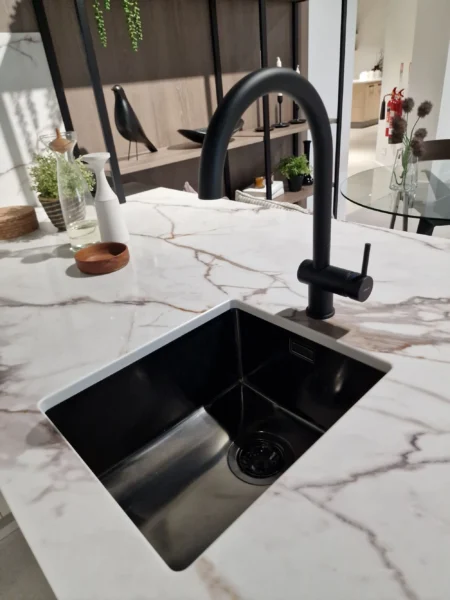 A black undermount sink with a black tap in a modern kitchen.