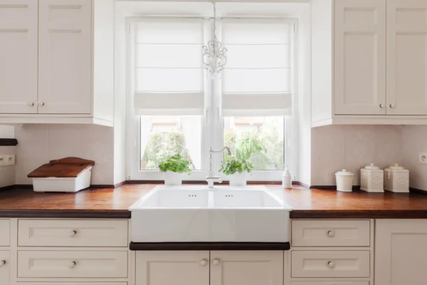 A white double farmhouse sink in a traditional kitchen.