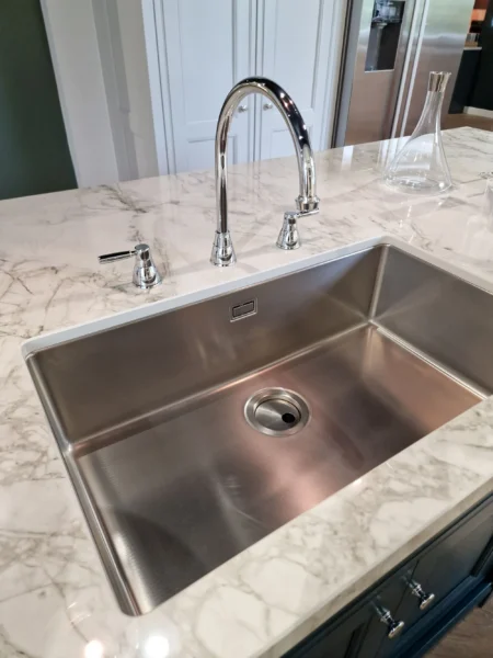 A large, stainless steel undermount sink with a chrome tap.