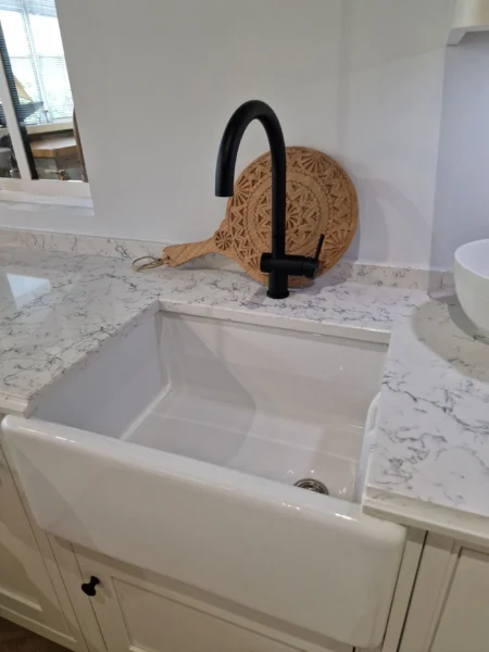 A farmhouse-style kitchen sink with a black tap.
