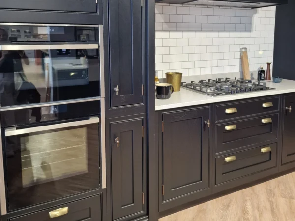 An royal blue, nearly black in frame kitchen with white splashback tiles behind the hob.