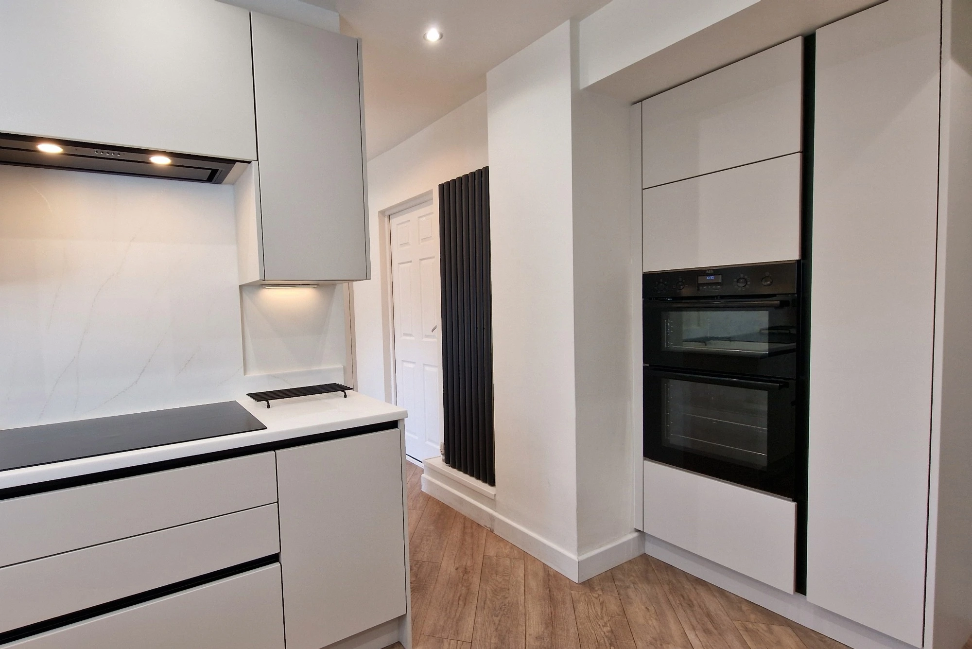 A sleek kitchen with handle-less cabinets, integrated appliances, and monochromatic colour scheme.