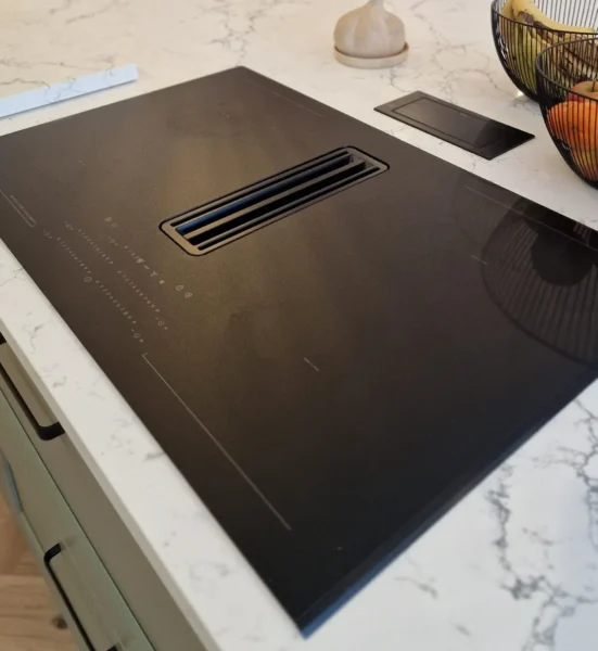 Black flat touch hob on a marbled kitchen island.