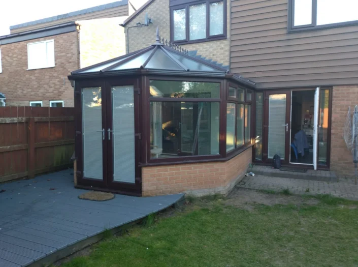 A rear extension on a house with dark brown wooden framing on the doorframe and glass roof.