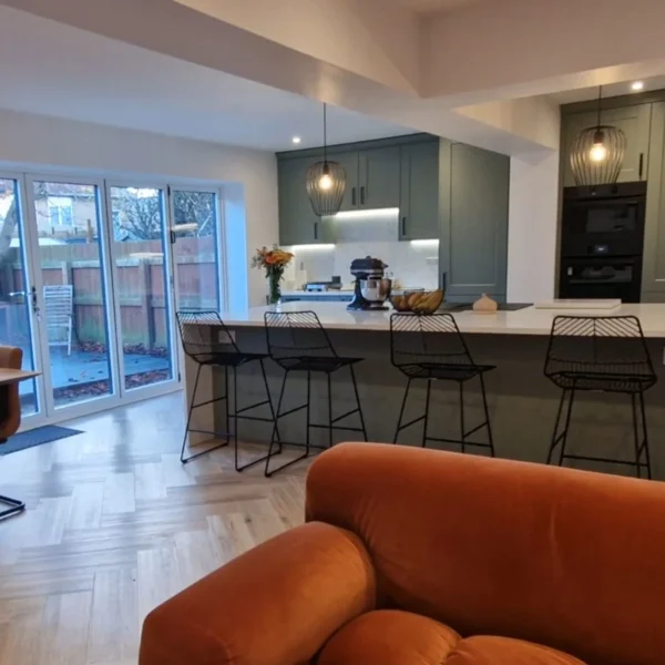 A kitchen with white and sage green walls, a large central island and a sofa.