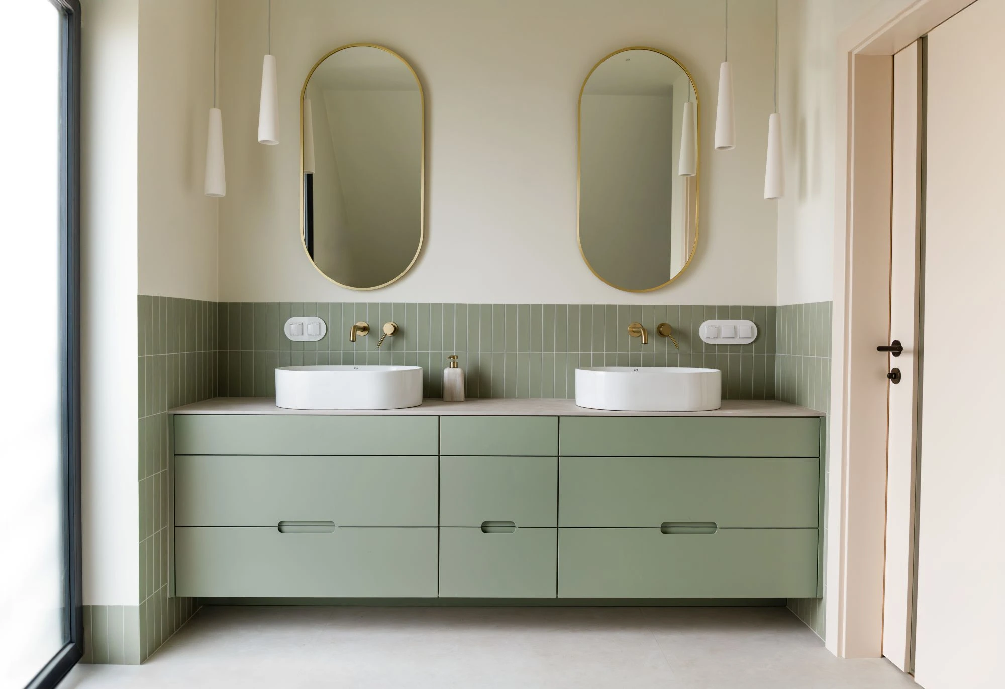 High-end bathroom with sage green cabinetry and tiling on walls.