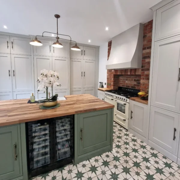 A mock in frame kitchen with a mixture of sage green and light grey cabinetry and decorative floor tiles.