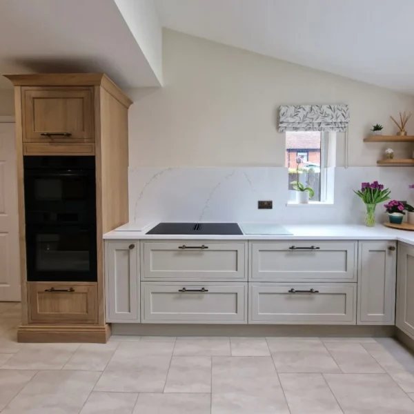 A modern mock in frame kitchen with white cabinetry, a white marble backsplash, and natural stone tiles on the floor.